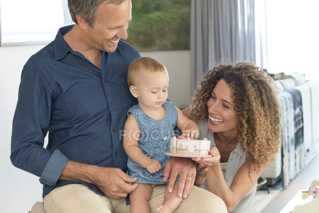 Happy woman giving toy to baby daughter sitting on father lap — Stock Photo