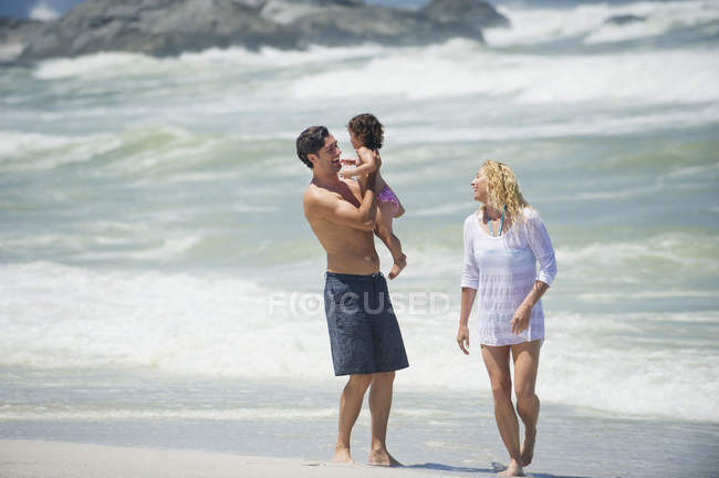 Coppia che cammina sulla spiaggia con figlioletta — Foto stock