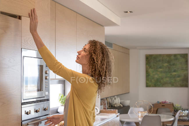 Mulher em roupa casual gaveta de abertura na cozinha — Fotografia de Stock