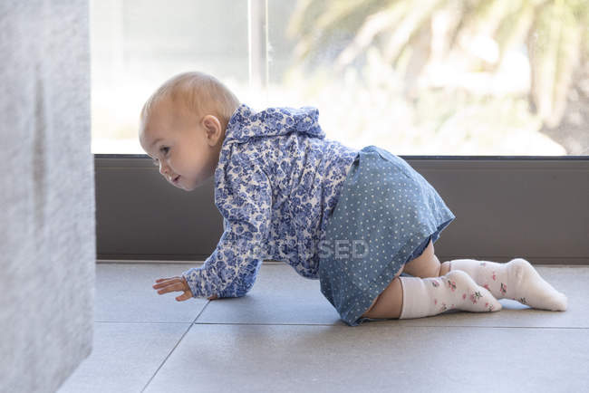 Baby girl crawling on floor at home — Stock Photo