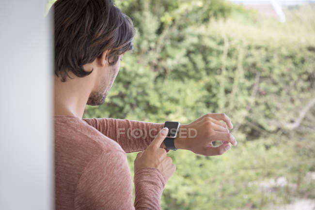 Young man checking time with smartwatch in garden — Stock Photo