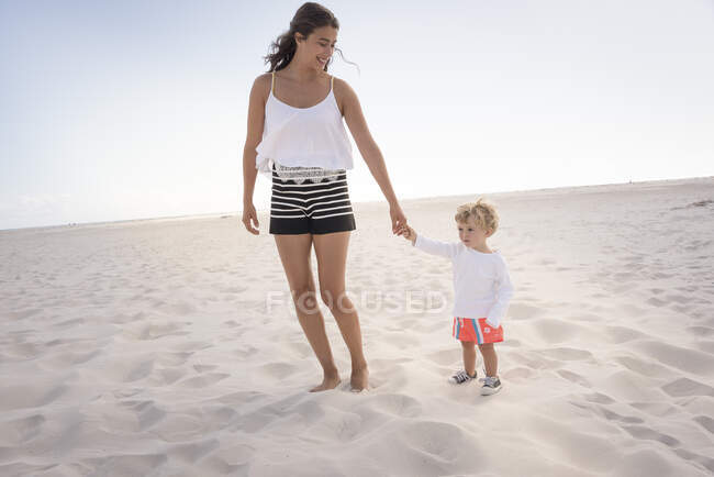 Щаслива мати зі своїм маленьким сином ходить на пляжі — стокове фото