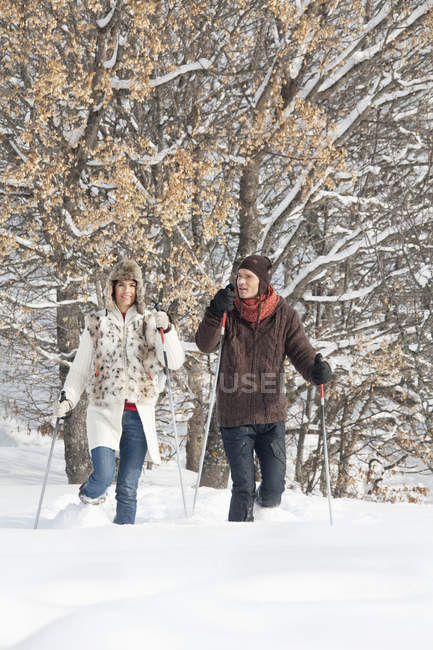 Giovane coppia racchette da neve nella foresta invernale — Foto stock