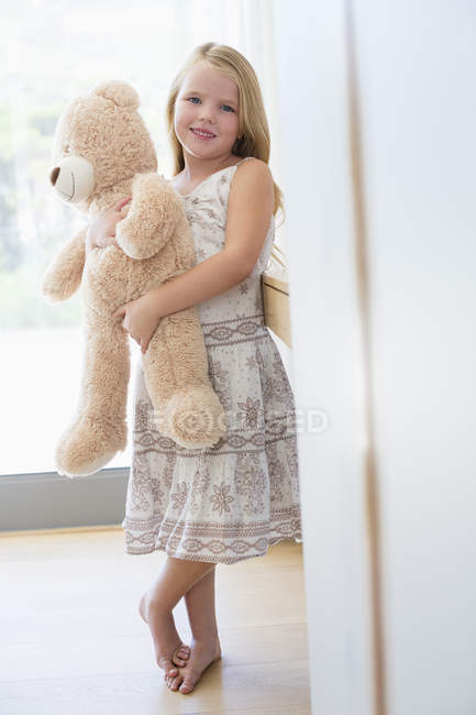 Portrait of cute little girl holding teddy bear at home — Stock Photo