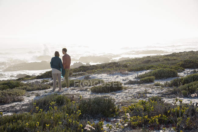Романтична пара стоїть на морському узбережжі і дивиться на погляд — стокове фото
