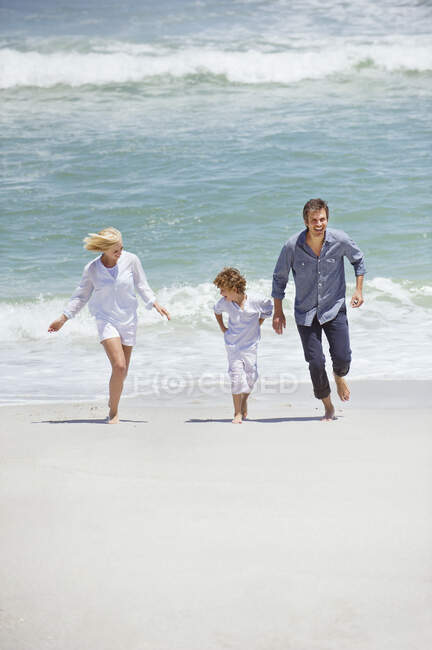 Пара з сином біжить на пляжі — стокове фото