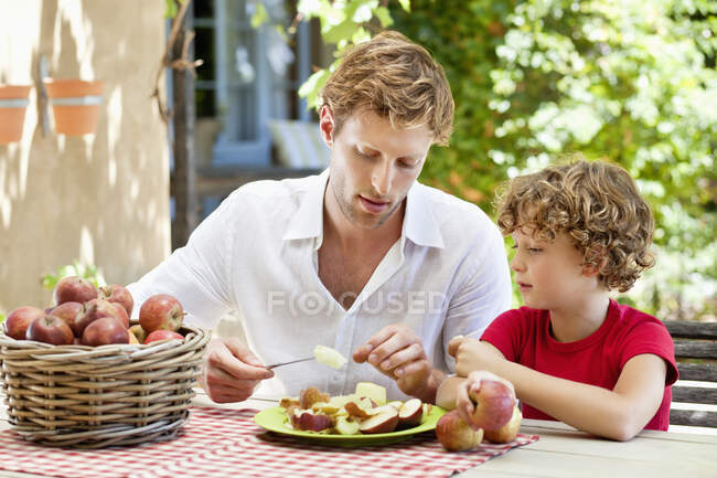 Padre pelando manzana con hijo - foto de stock