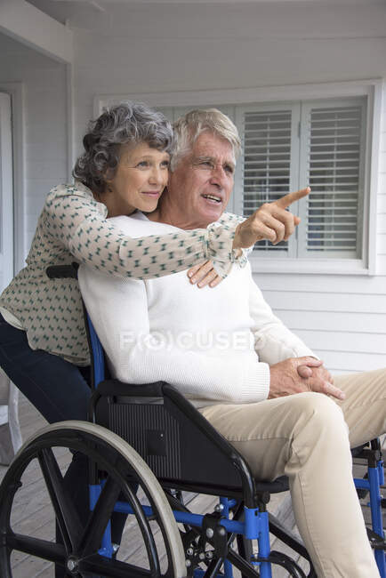 Homem sênior em cadeira de rodas com sua esposa na varanda — Fotografia de Stock