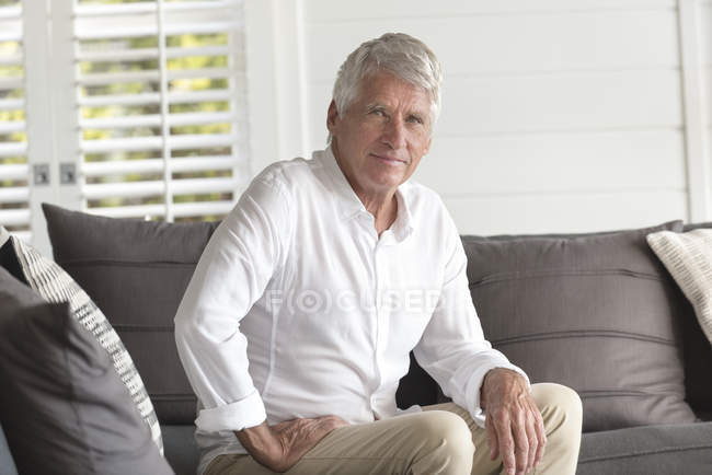 Retrato de hombre mayor feliz sentado en casa - foto de stock