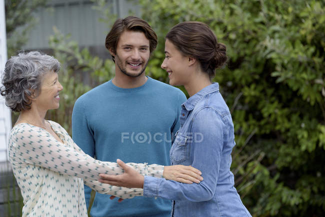 Happy mature woman greeting young couple outdoors — Stock Photo