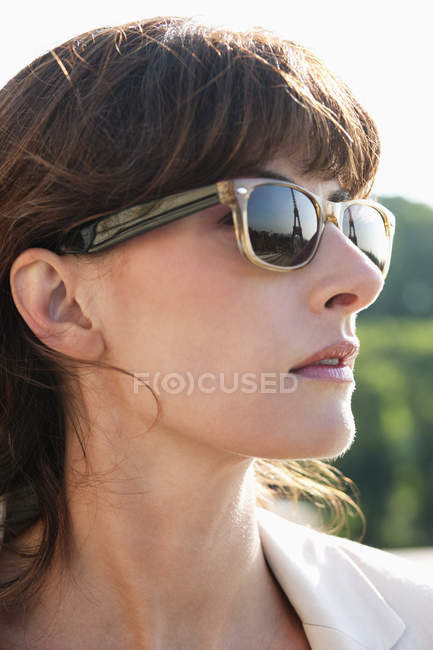 Gros plan sur une femme élégante et sérieuse portant des lunettes de soleil détournant les yeux — Photo de stock
