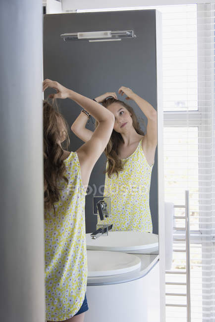 Adolescente menina examinando o cabelo no espelho — Fotografia de Stock