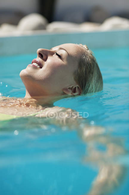 Gros plan de la femme souriante se relaxant dans la piscine — Photo de stock