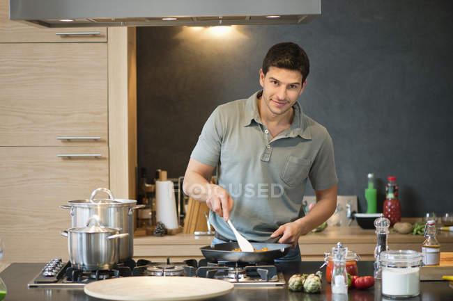 Mann bereitet Essen in Küche zu und schaut in Kamera — Stockfoto
