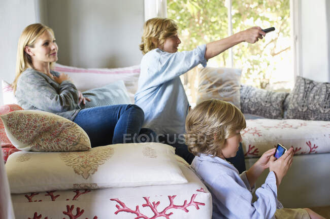 Los niños y la madre usando aparatos electrónicos en casa - foto de stock