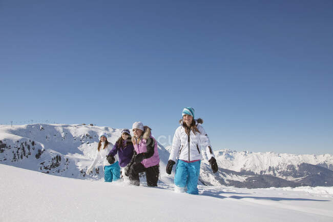 Чотири дівчини-підлітки в лижному одязі, що йдуть снігом — стокове фото