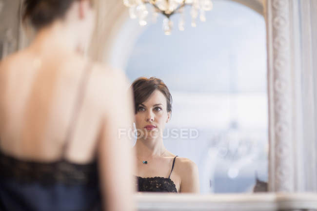 Reflexão da mulher elegante em vestido de noite olhando para o espelho — Fotografia de Stock