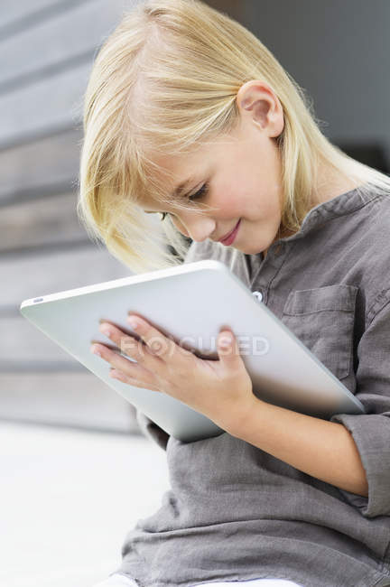 Linda chica rubia usando una tableta digital - foto de stock