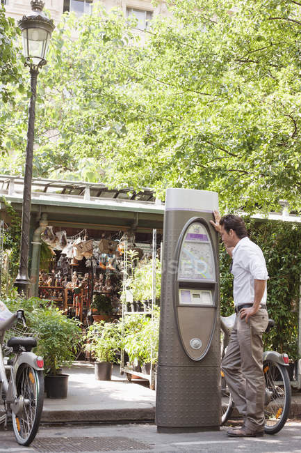 Hombre mirando el mapa en la máquina de boletos, Paris, Ile-de-France, France - foto de stock