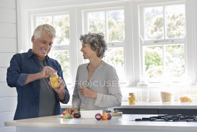 Happy senior couple preparing food in kitchen — Stock Photo