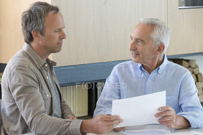 Reunión de hombres mayores con asesor financiero en casa - foto de stock