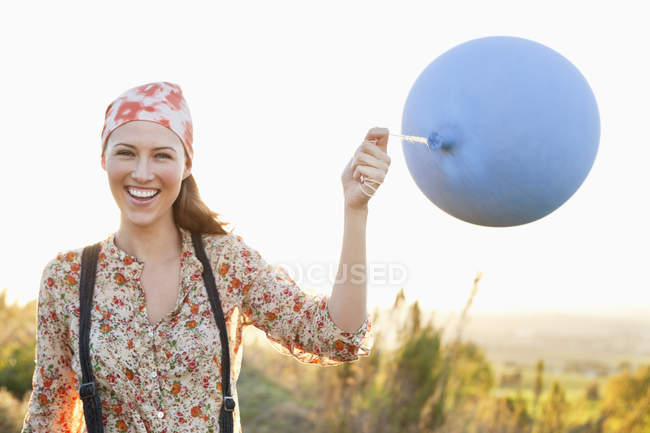 Портрет усміхненої жінки, що грає з повітряною кулею в природі — стокове фото