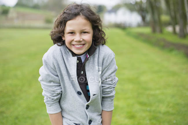 Портрет веселого мальчика, стоящего на зеленом поле — стоковое фото