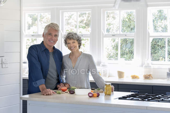 Retrato de feliz pareja de ancianos preparando comida en la cocina - foto de stock