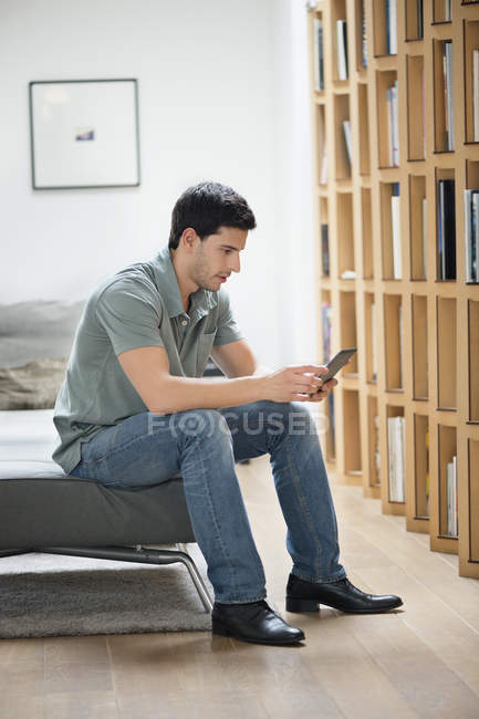 Mann sitzt auf Couch und liest zu Hause elektronisches Buch — Stockfoto