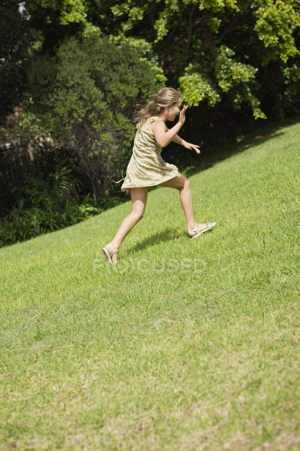 Веселая маленькая девочка играет в летнем саду — стоковое фото