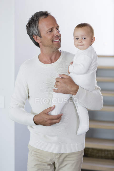 Pai feliz de pé com a filha bebê bonito em casa — Fotografia de Stock