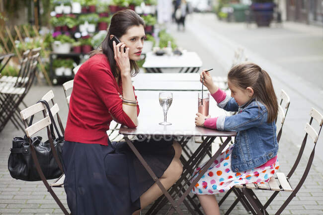 Mujer con su hija sentada en un café - foto de stock