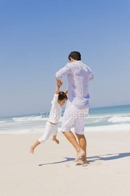 Мужчина играет со своим сыном на пляже — стоковое фото