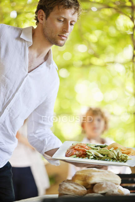 Junger Mann serviert Salat — Stockfoto