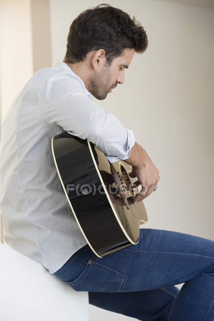 Rilassato uomo in camicia bianca suonare una chitarra — Foto stock