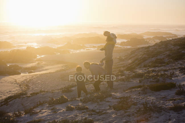 Familia caminando en la playa al atardecer brillante - foto de stock