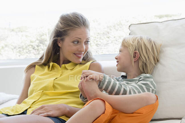 Mãe e filho felizes sentados no sofá na sala de estar — Fotografia de Stock