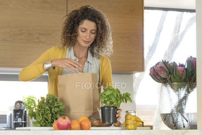 Женщина достает еду из бумажного пакета на кухне — стоковое фото