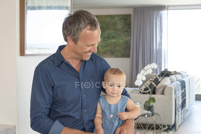 Happy mature man sitting with little daughter at home — Stock Photo