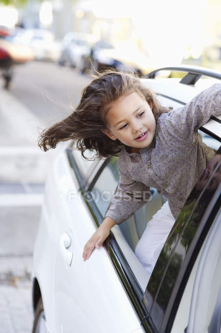 Petite fille mignonne regardant par la fenêtre de la voiture sur la rue — Photo de stock