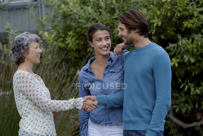 Happy mature woman greeting young couple outdoors — Stock Photo