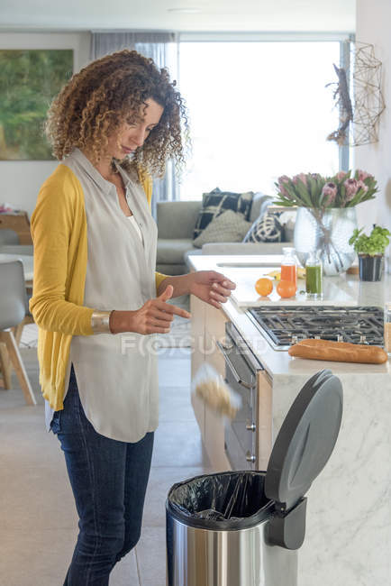 Femme jetant sachet de nourriture dans la poubelle dans la cuisine — Photo de stock