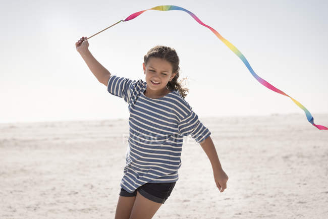 Happy girl jouer avec ruban coloré sur la plage — Photo de stock