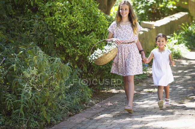 Happy siblings walking holding hands in garden — Stock Photo