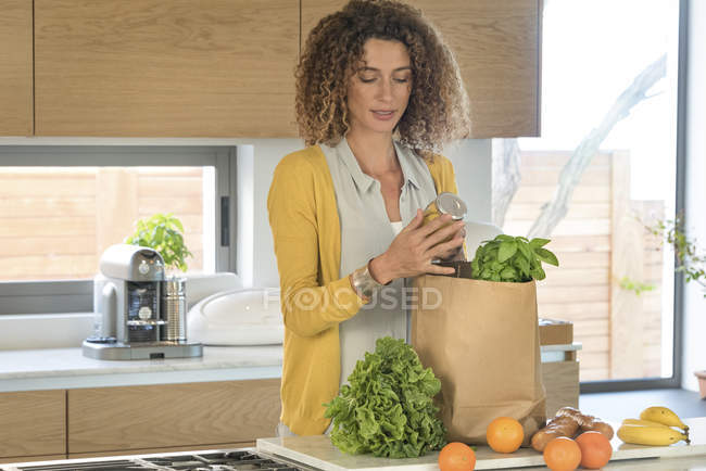 Frau holt Lebensmittel aus Papiertüte in Küche — Stockfoto