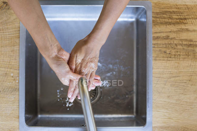 Primer plano de la mujer lavándose las manos en el fregadero de cocina - foto de stock