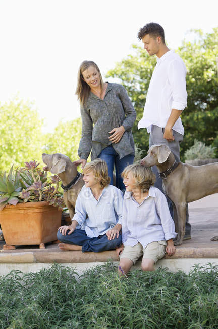 Щаслива сім'я розважається на задньому дворі з собаками — стокове фото
