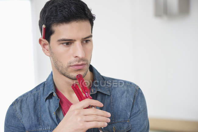 Pensativo técnico masculino sosteniendo destornilladores y pensando - foto de stock