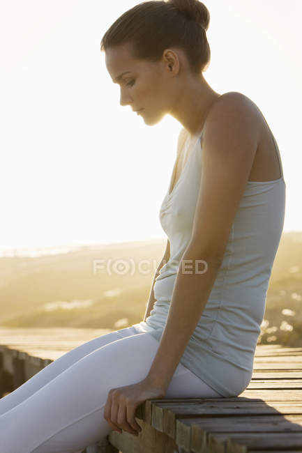 Елегантна жінка сидить на дошці на узбережжі — стокове фото