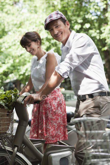 Sorrindo casal de pé bicicletas e falando na cidade — Fotografia de Stock